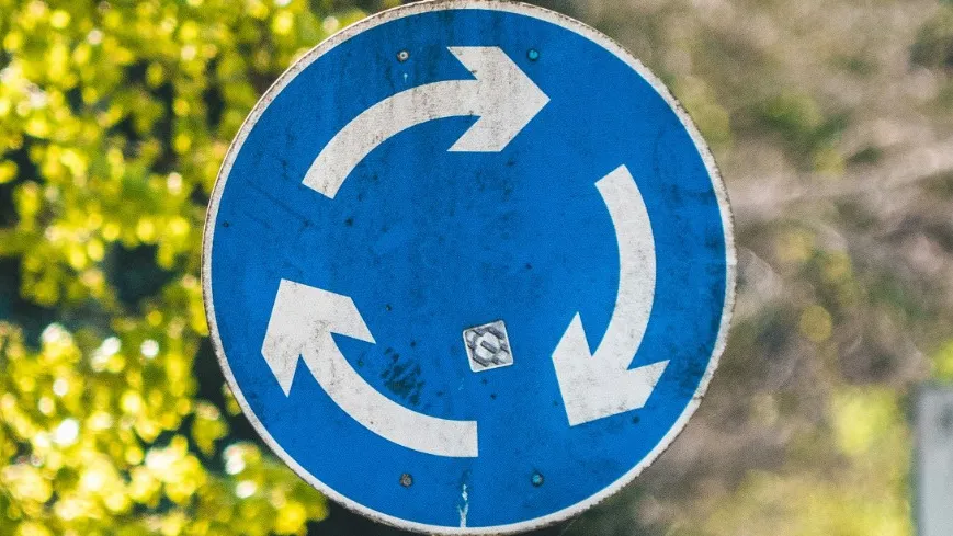 Ein rundes Schild mit weißen Pfeilen auf blauem Hintergrund 